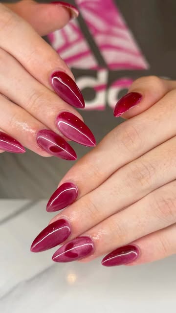 Glossy burgundy almond nails with fine curved accents by Foxy Nails and Spa