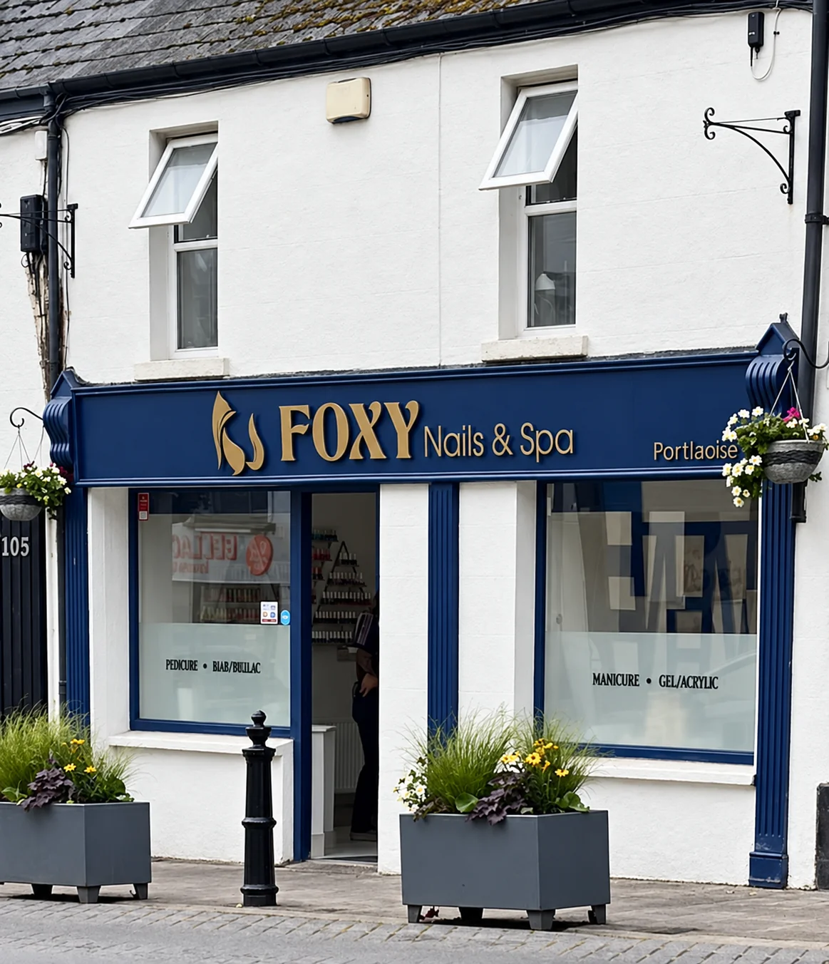 Foxy Nails and Spa storefront in Portlaoise with blue and gold signage and planters outside